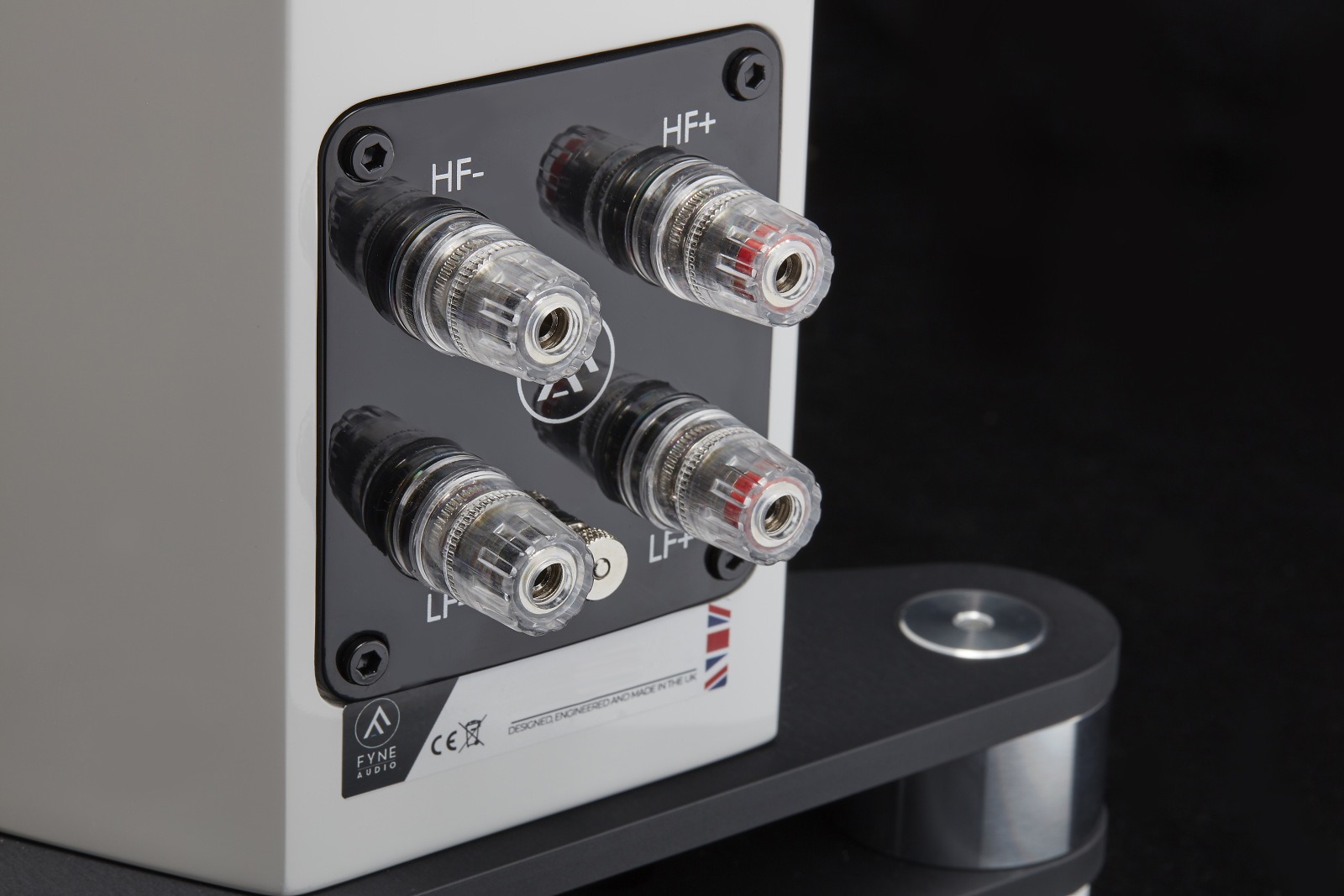 Four clear banana-plug connectors plugged into HF- and HF+ binding posts on a hi-fi amplifier rear panel.