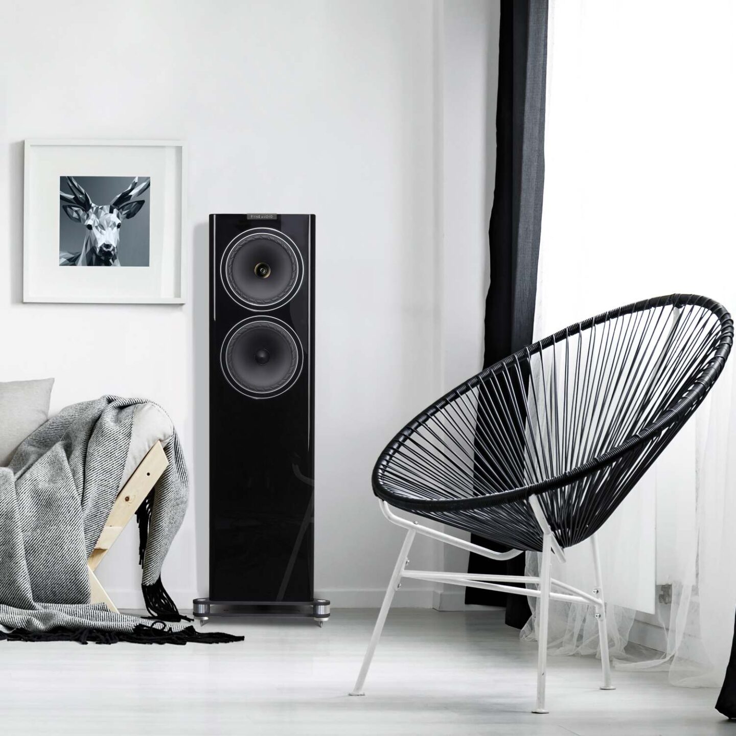 Напольные акустические системы Fyne Audio F702 в белой отделке (черная передняя панель) в интерьере около занавешенного окна и дизайнерского кресла